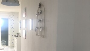 A hallway with a white tiled floor, a pendant light, a wall-mounted decorative item, and a chalkboard sign. - La Bouganville (Vibonati)