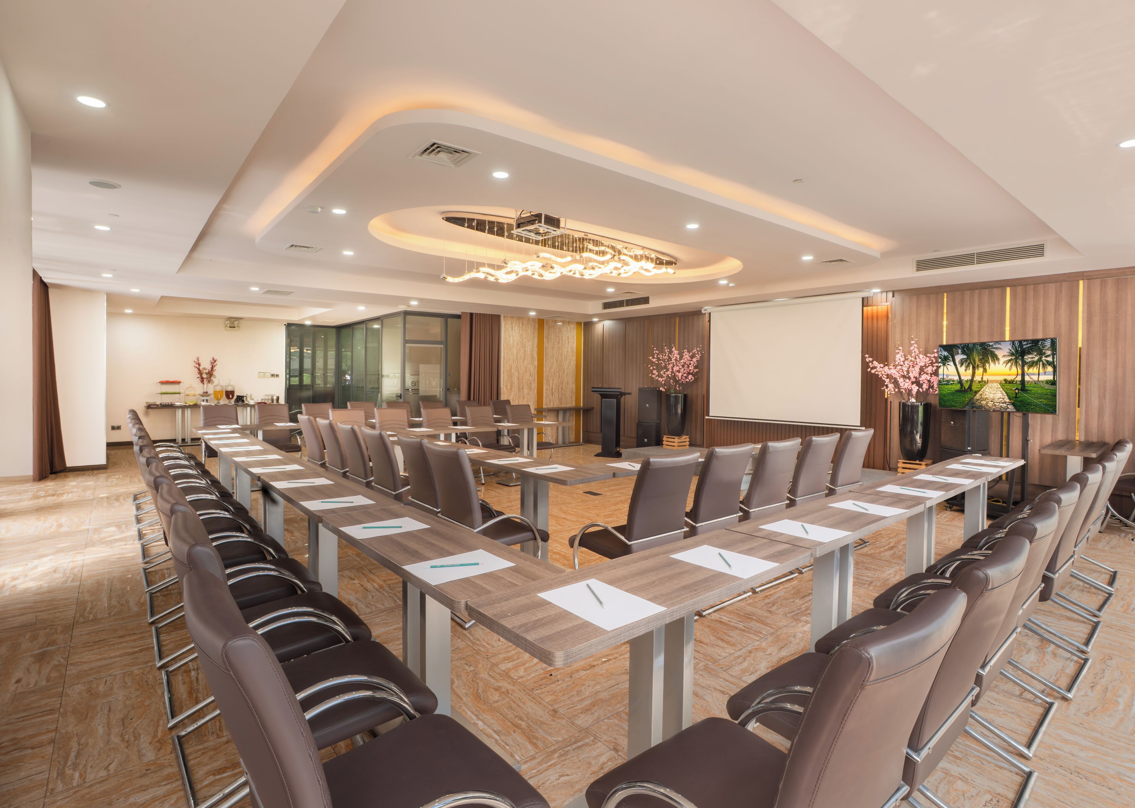 Une salle de conférence équipée d’une longue table, de chaises, d’un écran de projection et d’un grand écran.