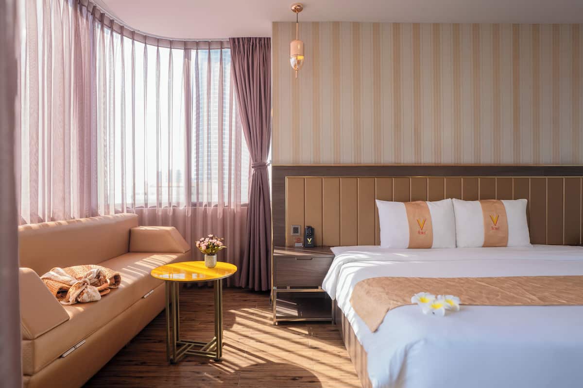 A hotel room with a sofa, a bed, a small table, and a nightstand.