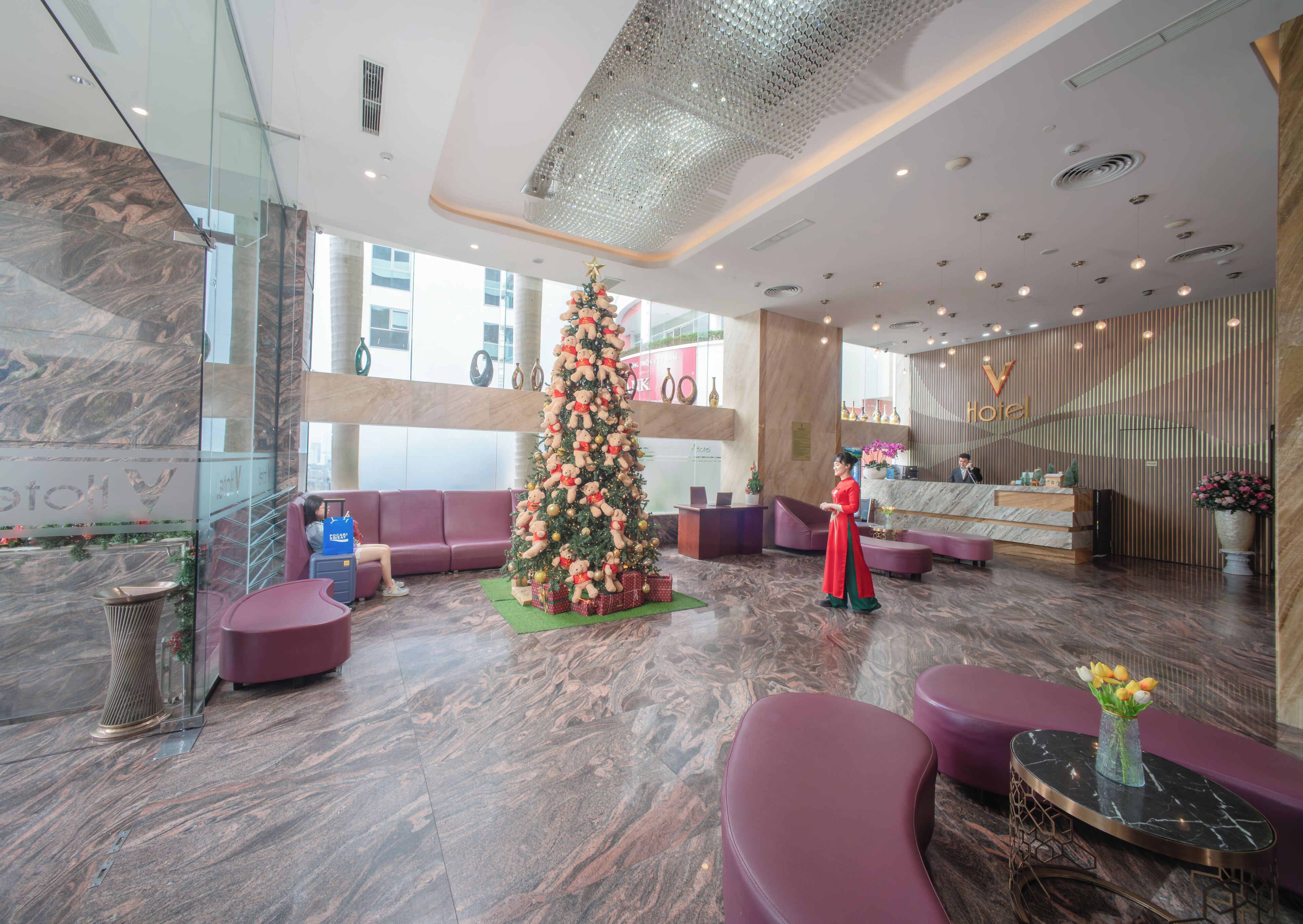 Een lobby met een kerstboom, zithoeken en een receptiebalie.