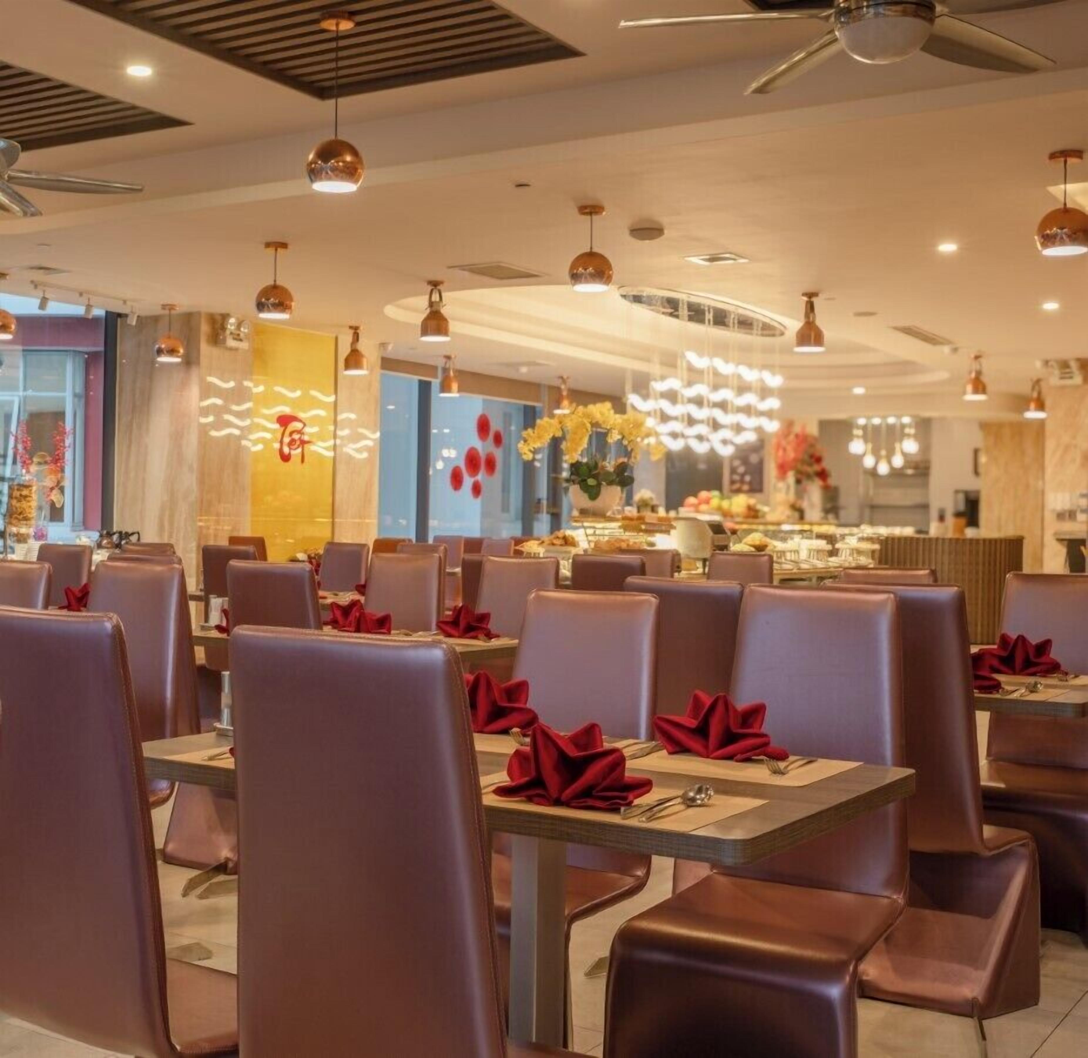 A restaurant interior with booths and tables, ceiling fans, and decorative lighting.