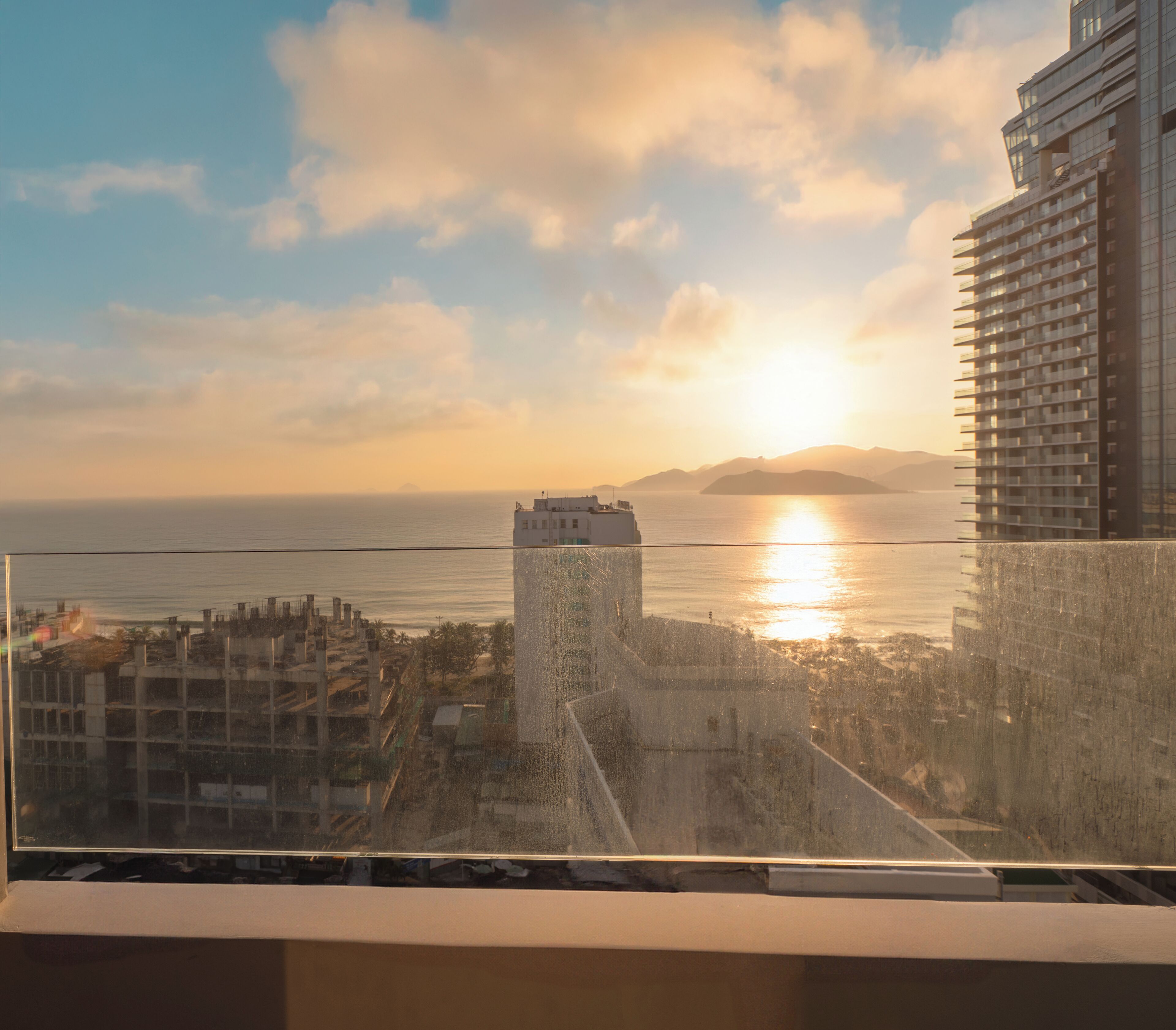 A high-rise building with a view of the sea and a sunset.