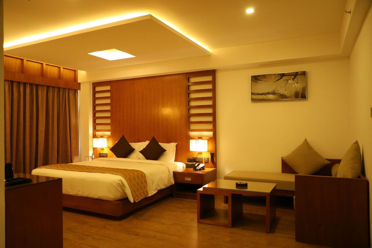 Een hotelkamer met een groot bed, nachtkastjes, een bureau en een stoel.