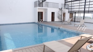 Una piscina interior con sillones de descanso y una escalera de caracol.