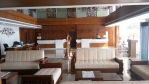 Un vestíbulo amplio con dos sofás, un mostrador de recepción y una estatua decorativa.