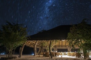 Una estructura con techo de paja, con asientos al aire libre y vista al cielo estrellado.