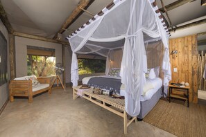 A bedroom with a canopy bed, a wooden bench, a camera on a tripod, and a rustic wooden wall.