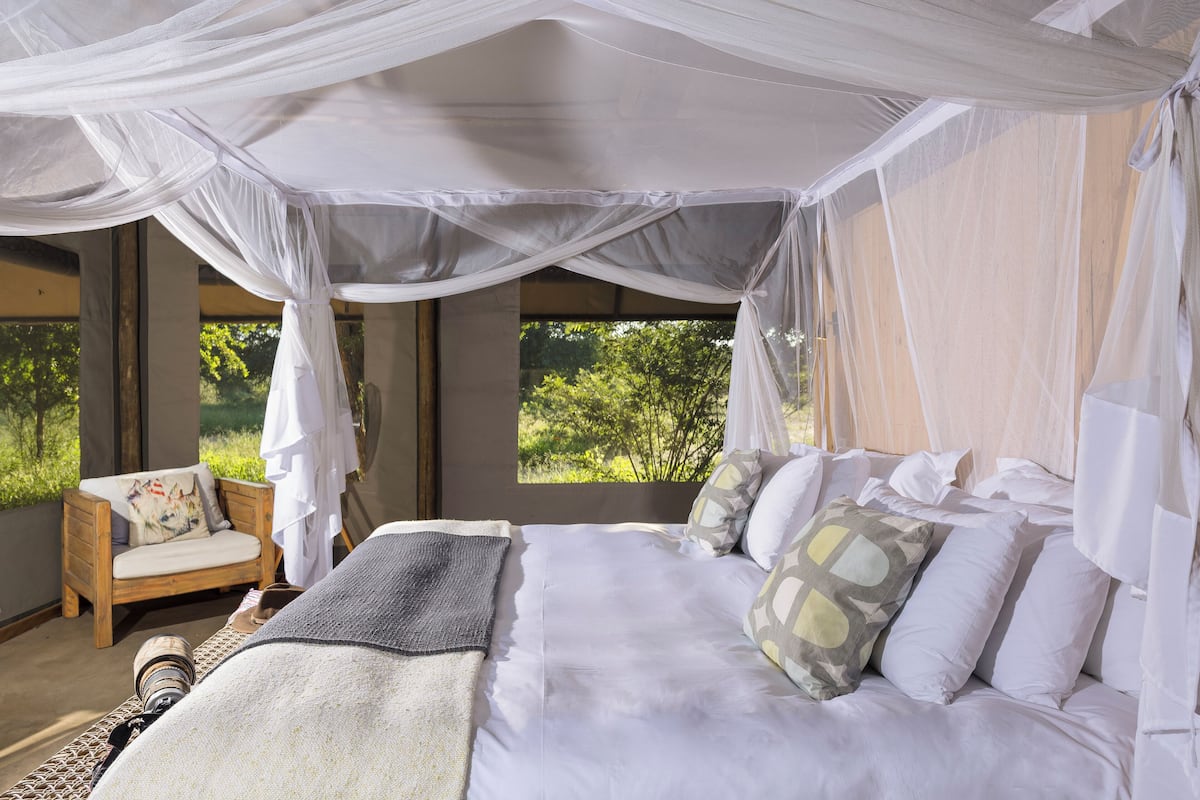 Un dormitorio con cama con dosel, una silla de madera y vistas al exterior.