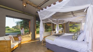 Une chambre à coucher avec un lit à baldaquin, un banc en bois et une grande fenêtre donnant sur un paysage verdoyant.