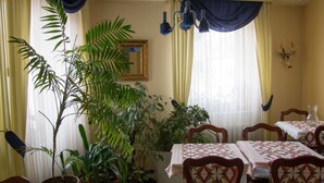 A dining area with multiple tables and chairs, surrounded by potted plants. - Hôtel de Bâle (Bantzenheim)