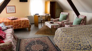 A cozy attic bedroom with two beds, a desk, and a chair. - Hôtel de Bâle (Bantzenheim)