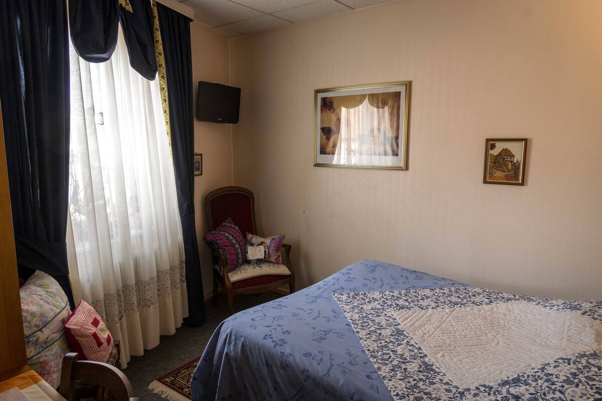 A bedroom with a bed, a chair, a television, and a framed picture on the wall.