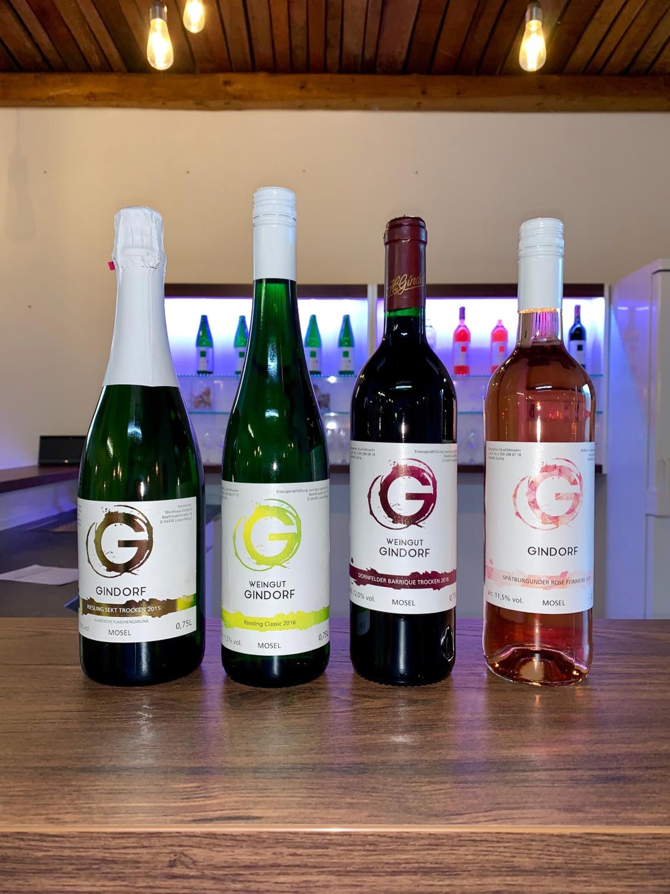 Cuatro botellas de vino con etiquetas sobre una superficie de madera.
