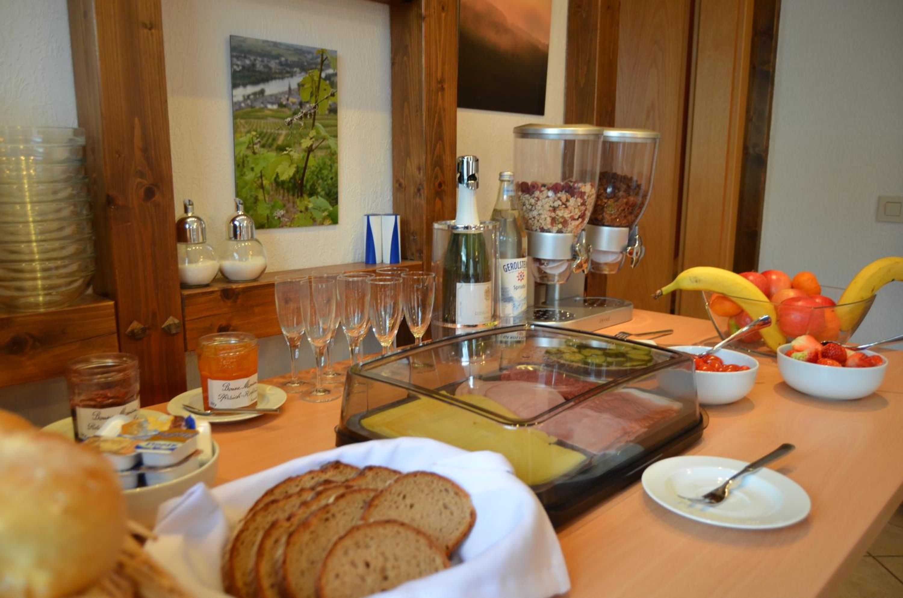 A buffet setup with various food items, including bread, fruits, and a beverage dispenser.