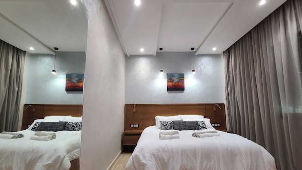 Une chambre d’hôtel avec deux lits, chacun agrémenté de serviettes soigneusement pliées, d’une tête de lit en bois et d’un tableau accroché au mur.
