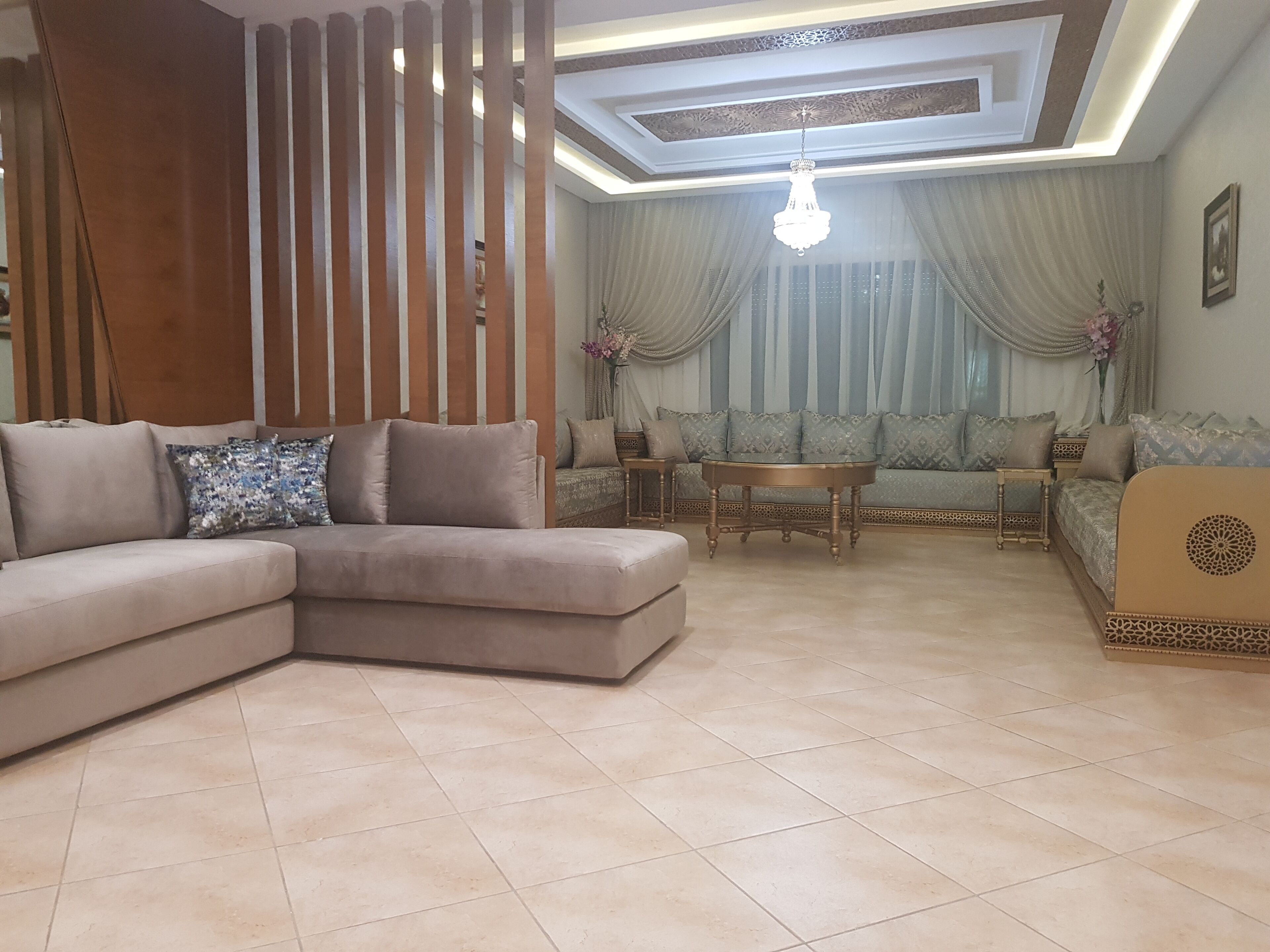 A living room with a sectional sofa, a round coffee table, and a patterned sofa set.