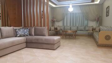 A living room with a sectional sofa, a round coffee table, and a patterned sofa set.