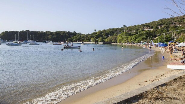 A beach with boats, a sandy shore, and a hilly background. - Village dos Ossos (Búzios)