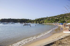A beach with boats, a sandy shore, and a hilly background. - Village dos Ossos (Búzios)