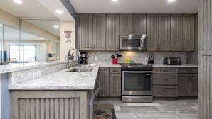 Eine moderne Küche mit Granit Arbeitsplatten, Edelstahlgeräten und Holzschränken.