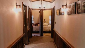 A narrow hallway with wooden paneling, a carpeted floor, and framed pictures on the walls. - Potter County Gasthaus - Full Lodge for Rent (Shinglehouse)