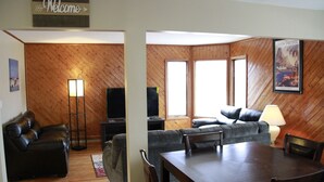 Un salon avec un mur en bois, un canapé, une table basse et un téléviseur.