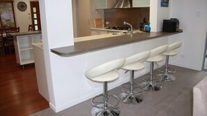 Eine moderne Küche mit Barbereich und drei weißen Barhocker.