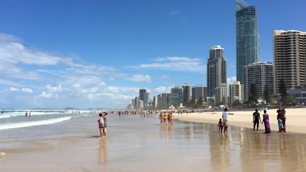 Ein Strand mit Menschen und Hochhäusern im Hintergrund.