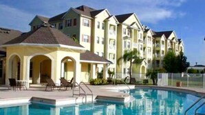 A hotel with a swimming pool, multiple balconies, and a clear blue sky. - WATER VIEW*4 Bedroom/Elevator/5 Star Condo* DISNEY Area (Kissimmee)