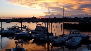 A marina with boats docked at calm water during sunset. - Romantic Summerwind Cottage-Harbor View Retreat w/Large Private Deck (Gloucester)