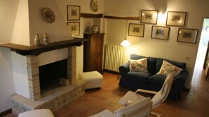 Una sala de estar con chimenea, un sofá, un sillón y una lámpara.