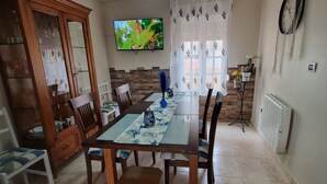 Un comedor con una mesa, sillas, un televisor y un armario.