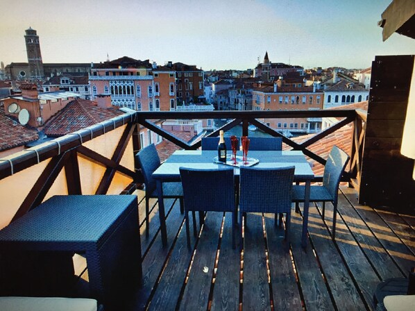 A terrace with a table and chairs, overlooking a cityscape with historic buildings.