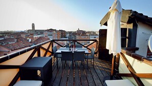 En tagterrasse med bord og stole med udsigt over en by silhuet med historiske bygninger.