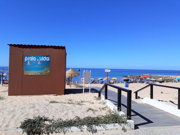 Une plage avec un panneau indiquant « Praia do Viadul » et une promenade en bois menant à la plage.
