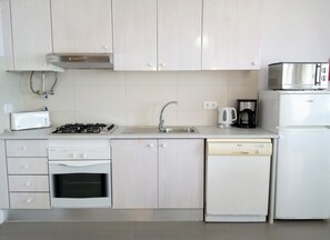 Une cuisine moderne avec des meubles blancs, une cuisinière à gaz, un lave-vaisselle, une machine à café et un four à micro-ondes.