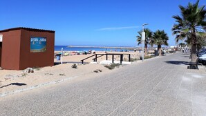Une promenade en bord de mer, avec une pancarte indiquant « Praia do Vial », un sentier pavé, des palmiers et la mer en arrière-plan.