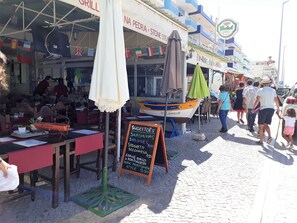 Un área de comedor al aire libre con mesas y sillas, un bote y un menú en una pizarra.