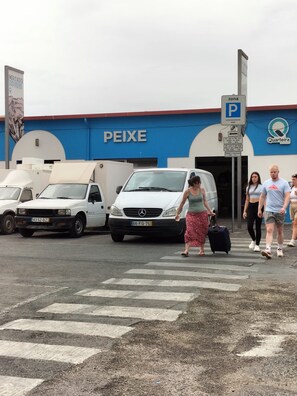 Un espace de stationnement avec un bâtiment bleu portant l’inscription « PEIXE » et un panneau indiquant la disponibilité des places de stationnement.
