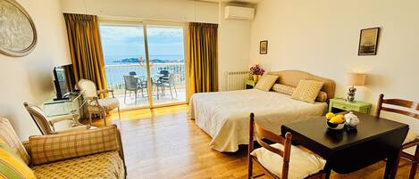 Una camera d'albergo con un letto, un tavolo da pranzo, una poltrona e un balcone con vista.