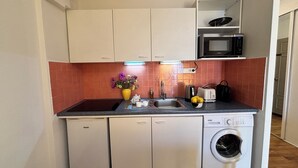 A compact kitchen with a washing machine, a microwave, and a sink. - Luxury Apartment block (Villefranche-Sur-Mer)