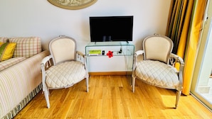A living room with a sofa, two armchairs, a glass coffee table, a flat-screen TV, and a wall-mounted decorative piece. - Luxury Apartment block (Villefranche-Sur-Mer)