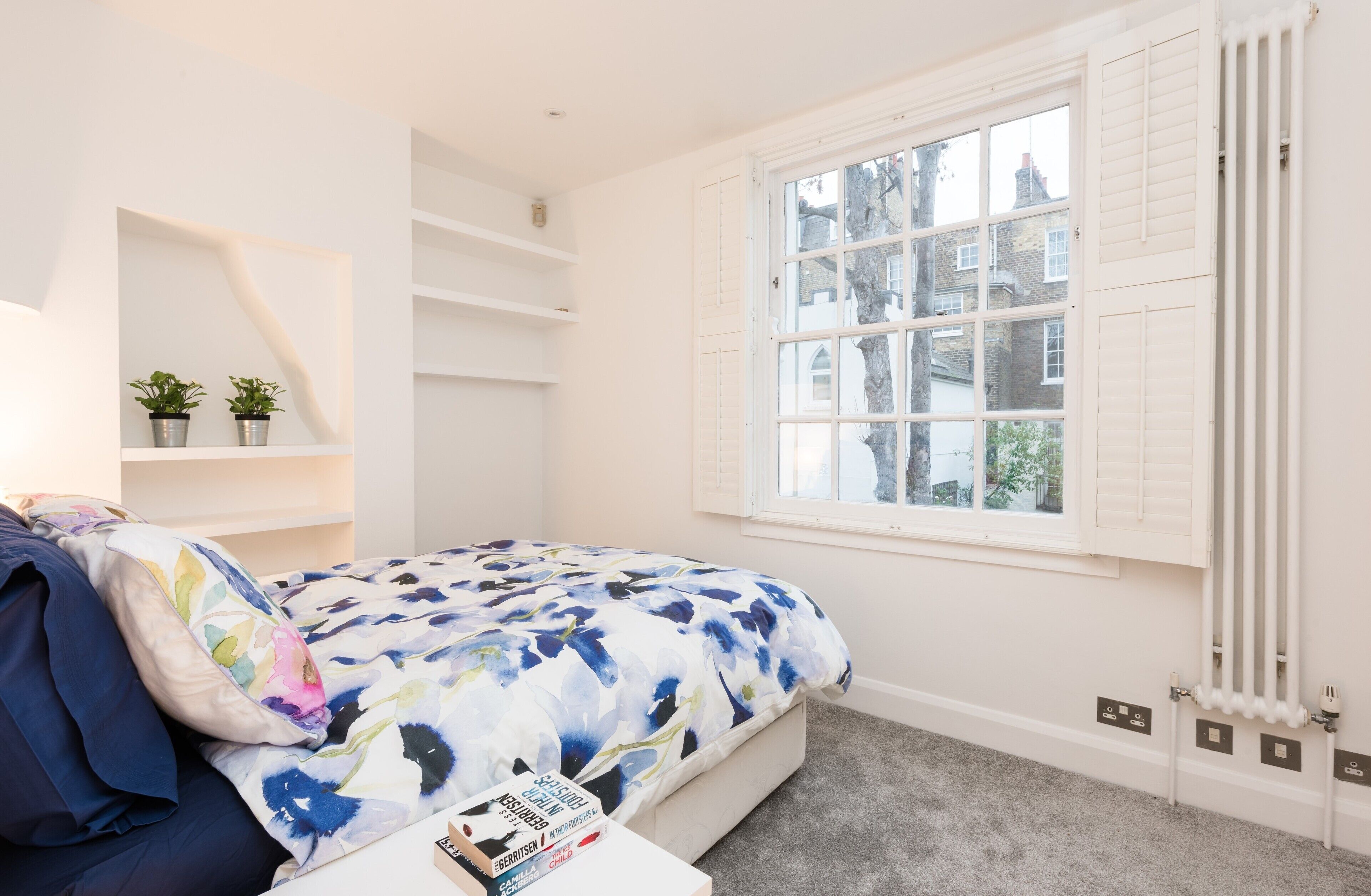 Un dormitorio con cama, ventana y radiador.