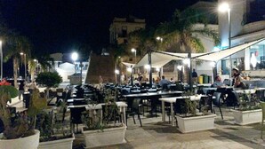 An outdoor dining area with tables and chairs, surrounded by potted plants and street lamps. - Guest House Adele-Marina Di Ragusa (Marina di Ragusa)
