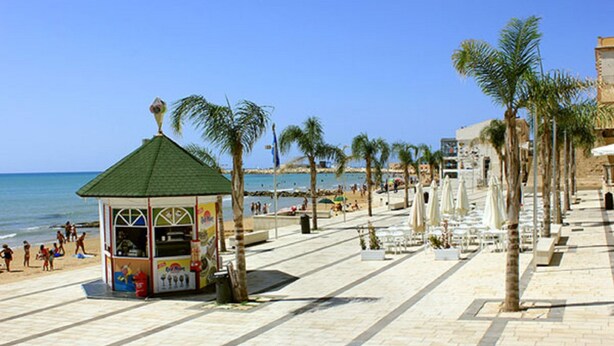 A beachside promenade with palm trees, a kiosk, and beachgoers. - Guest House Adele-Marina Di Ragusa (Marina di Ragusa)