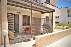 Ein Balkon mit Metallzaun, Korbstühlen und Topfpflanzen.
