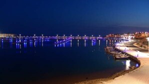 A waterfront promenade with a series of docks and a bridge, illuminated by blue lights. - Guest House Adele-Marina Di Ragusa (Marina di Ragusa)
