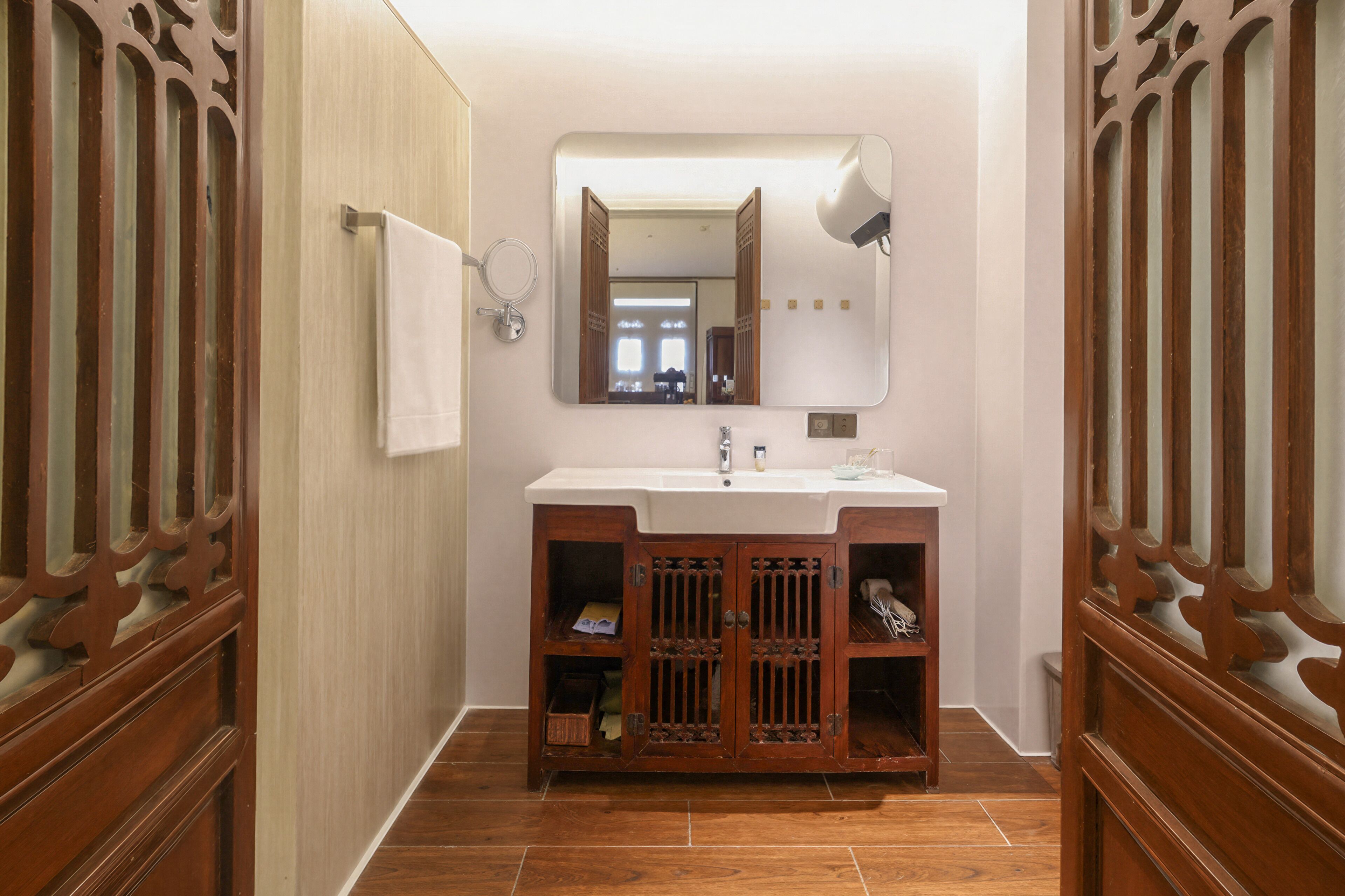 Une salle de bain avec un meuble-lavabo en bois, un miroir, un porte-serviettes et un lavabo.