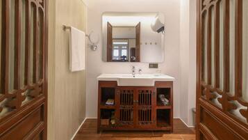 Une salle de bain avec un meuble-lavabo en bois, un miroir, un porte-serviettes et un lavabo.