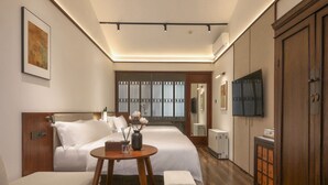 Quarto de hotel com duas camas, uma televisão, um armário de madeira e uma pequena mesa com um vaso.